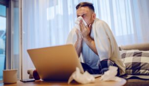 Sick employee blowing nose into tissue